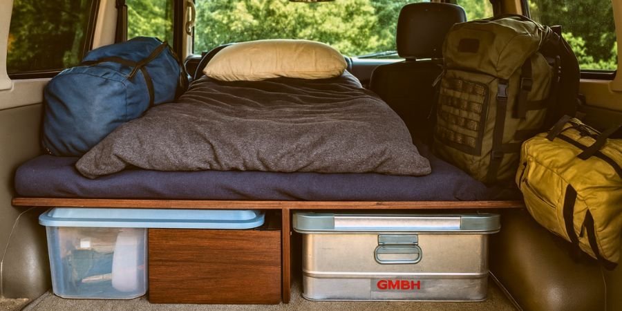 Interior de un vehículo preparado para camping overland con cama y equipo básico