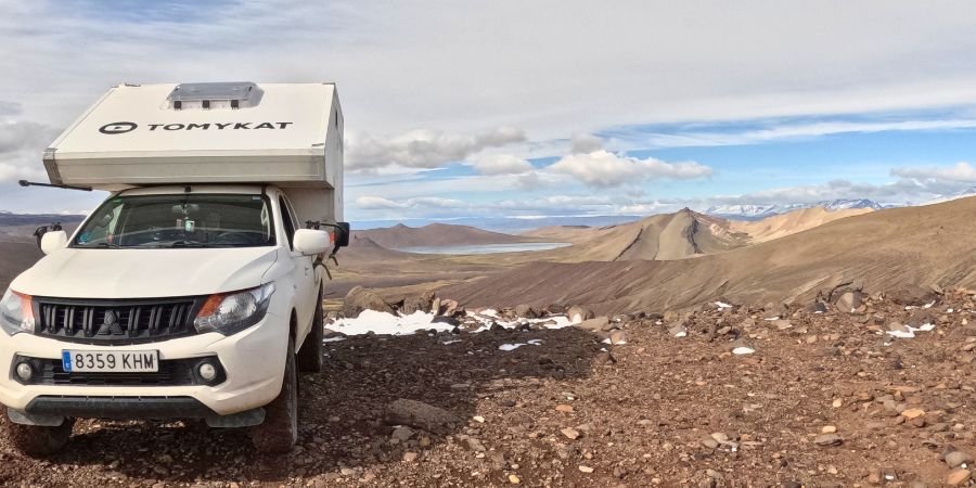 Vehículo todoterreno en ruta de overlanding Con montañas y lago al fondo