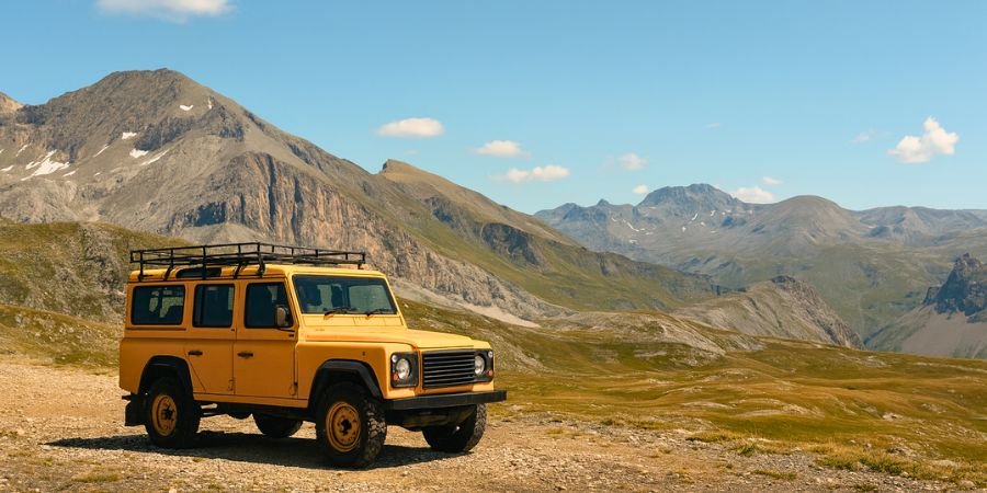 Coche todo  terreno en lo alto de una montaña con paisaje de fondo