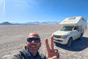 Viajero overland Tomy junto a su vehículo 4x4 en paisaje abierto